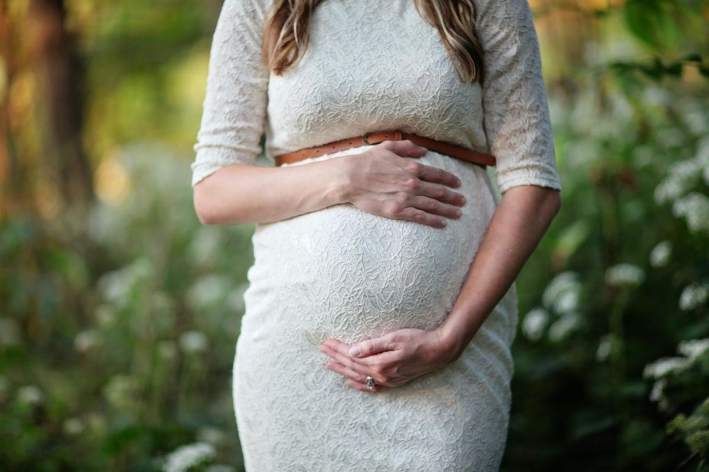 Mulher grávida com as mãos na barriga