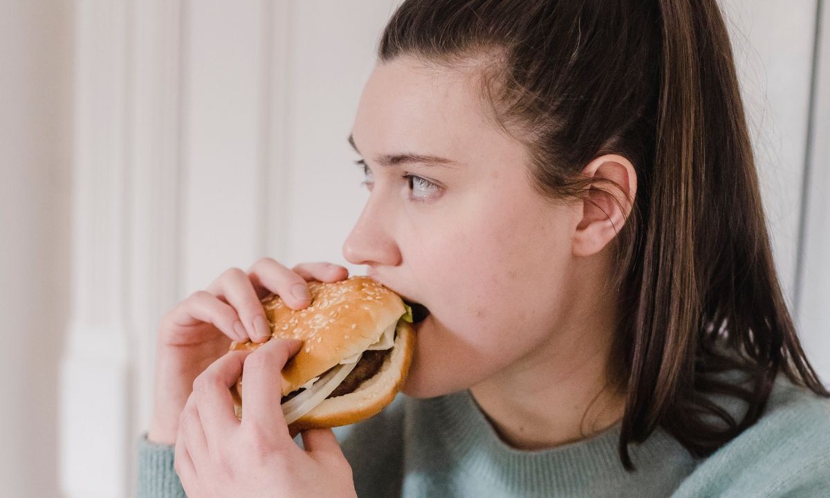 Mulher comendo hambúrguer no dia flexível