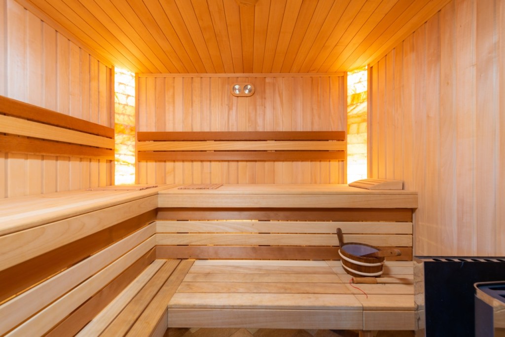 Sala coberta de madeira com bancos também de madeira e iluminação quente.