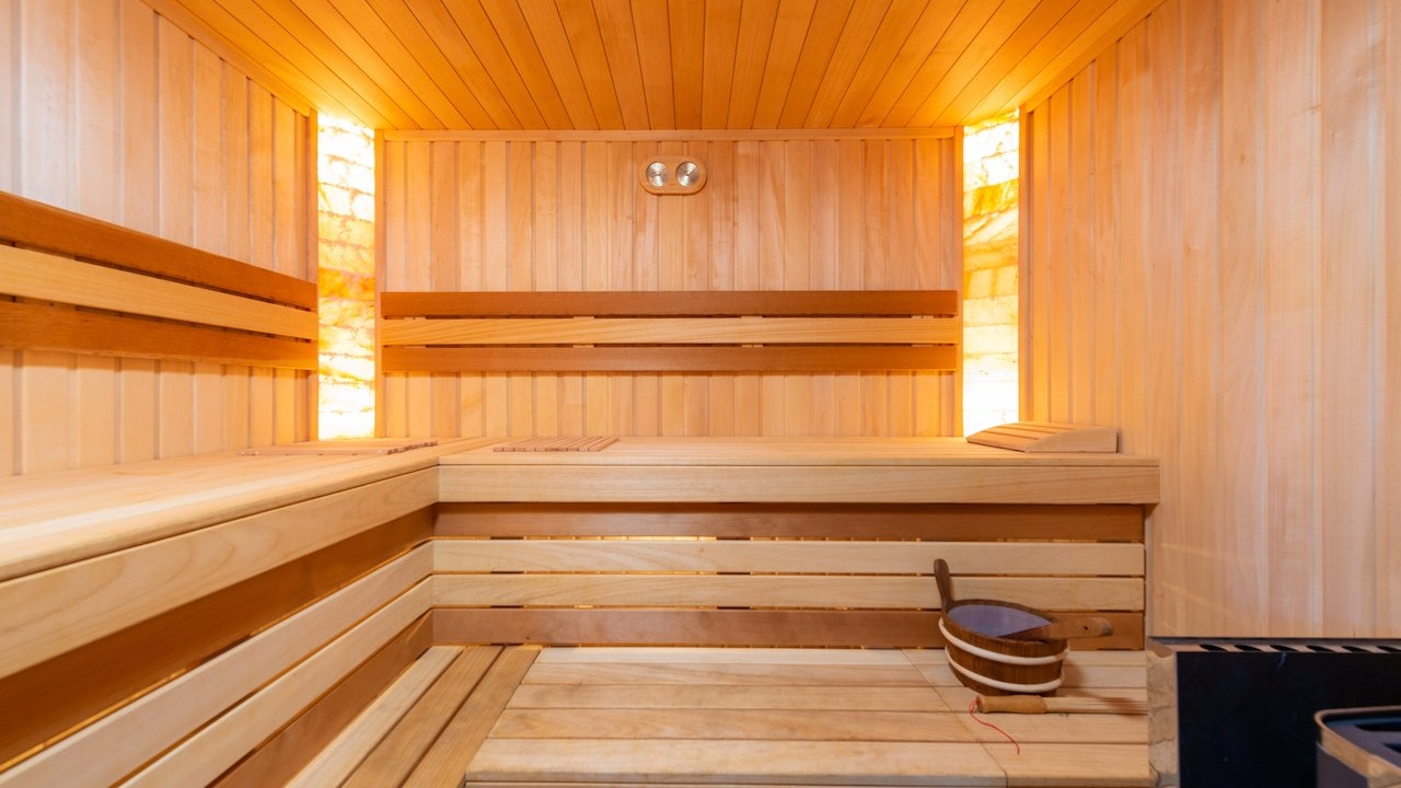 Sala coberta de madeira com bancos também de madeira e iluminação quente.