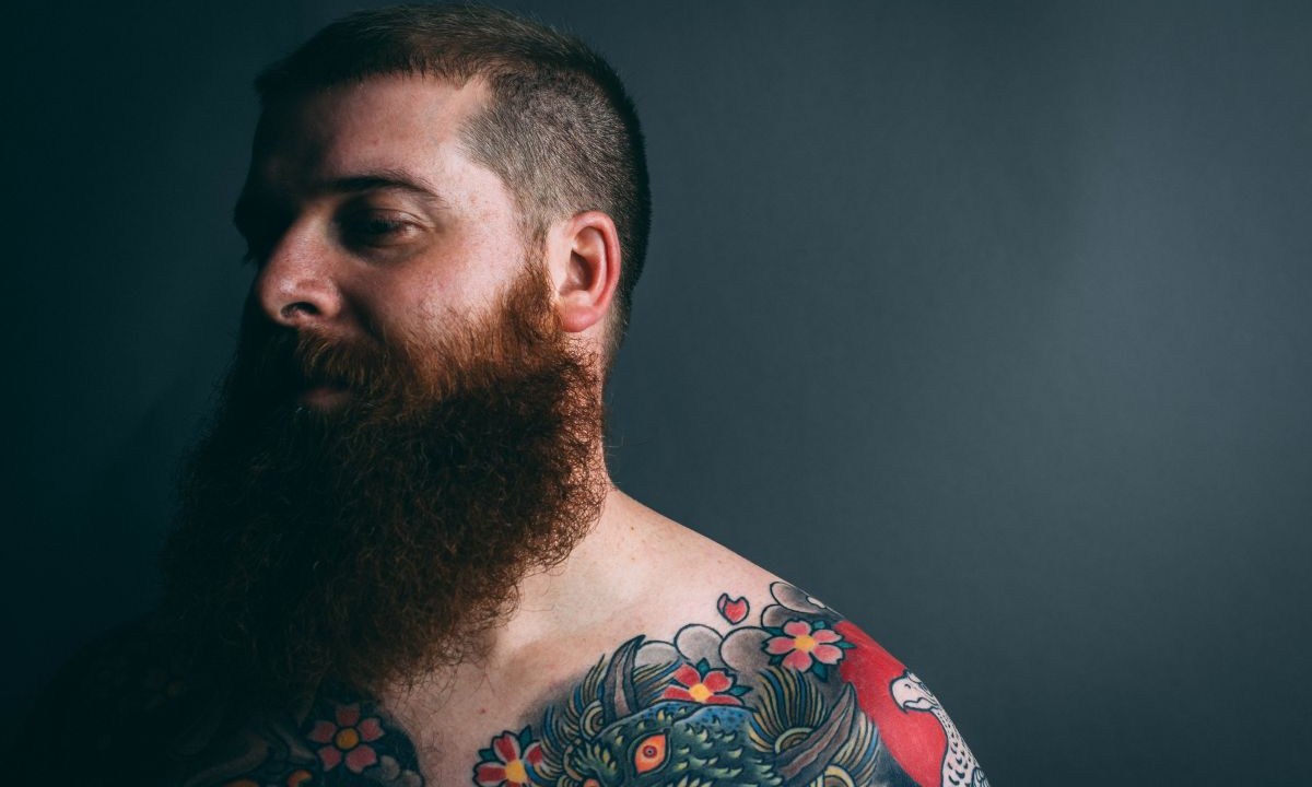Homem barbudo com tatuagens no corpo