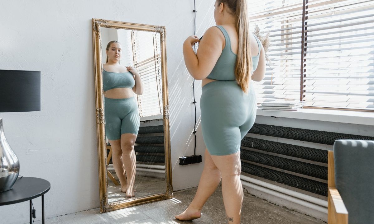 Mulher gorda se olhando no espelho