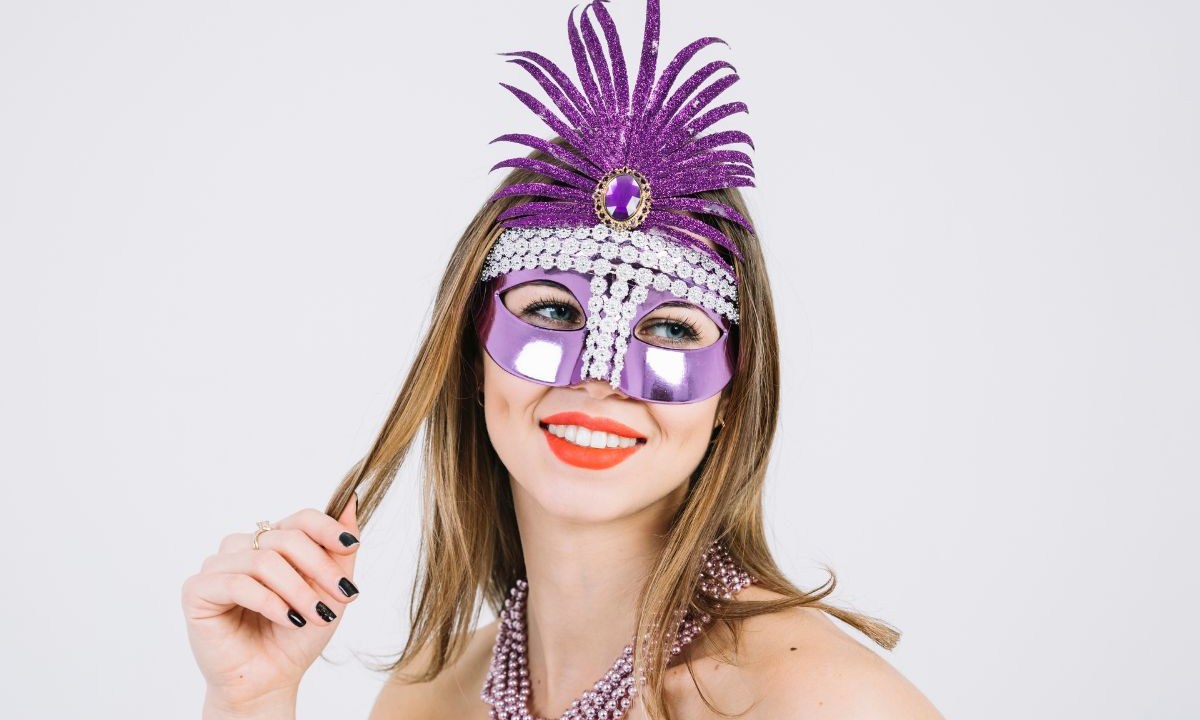 Mulher com máscara de carnaval segurando uma mecha do seu cabelo