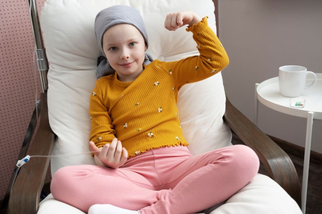 Criança com blusa amarela recebendo tratamento de câncer