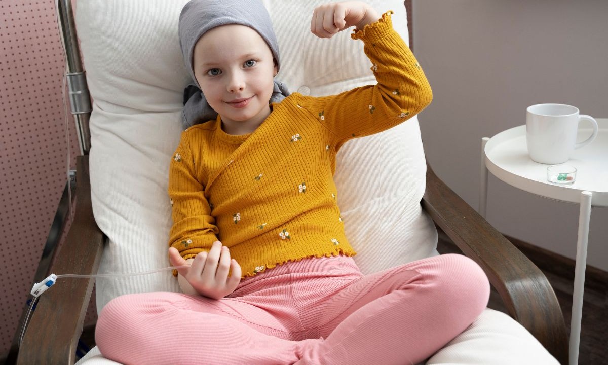 Criança com blusa amarela recebendo tratamento de câncer