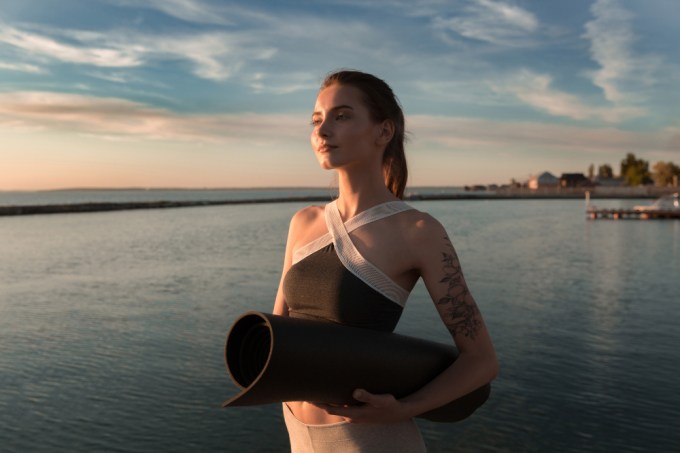 investimento para sua saúde | mulher na praia com mat de yoga