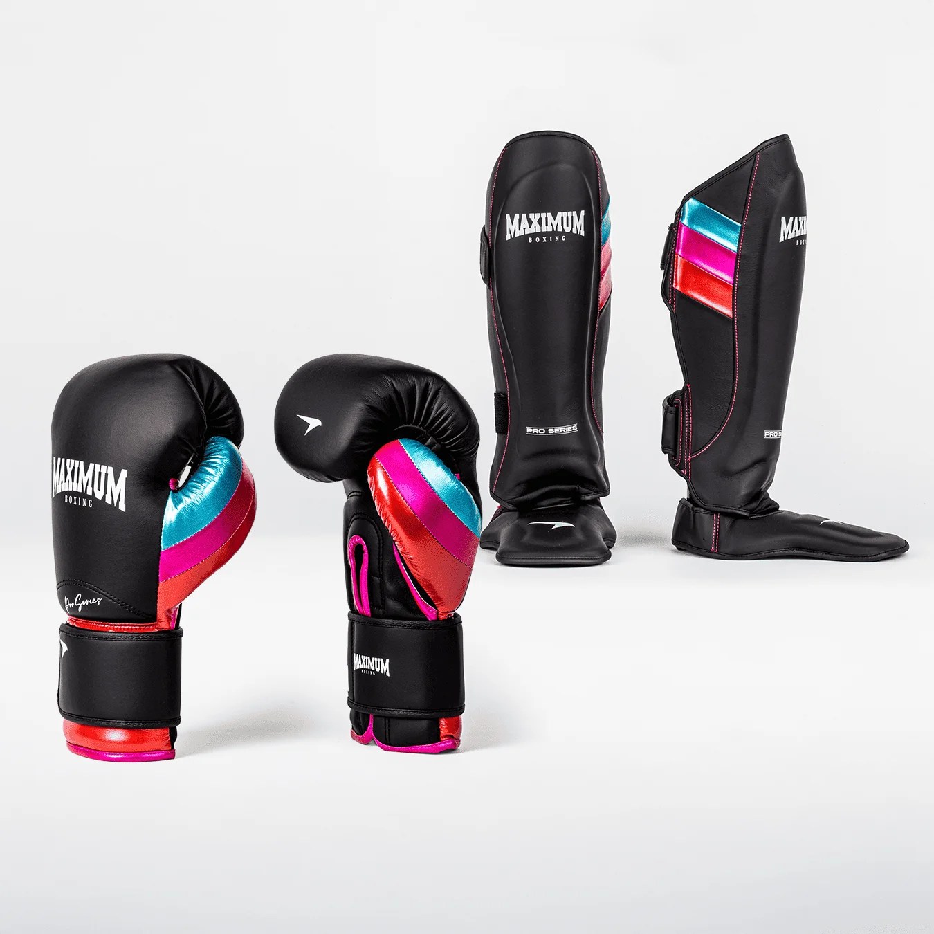 Luvas de boxe e caneleiras pretas com detalhes em azul turquesa, rosa choque e vermelho metálico, dispostos em um fundo branco