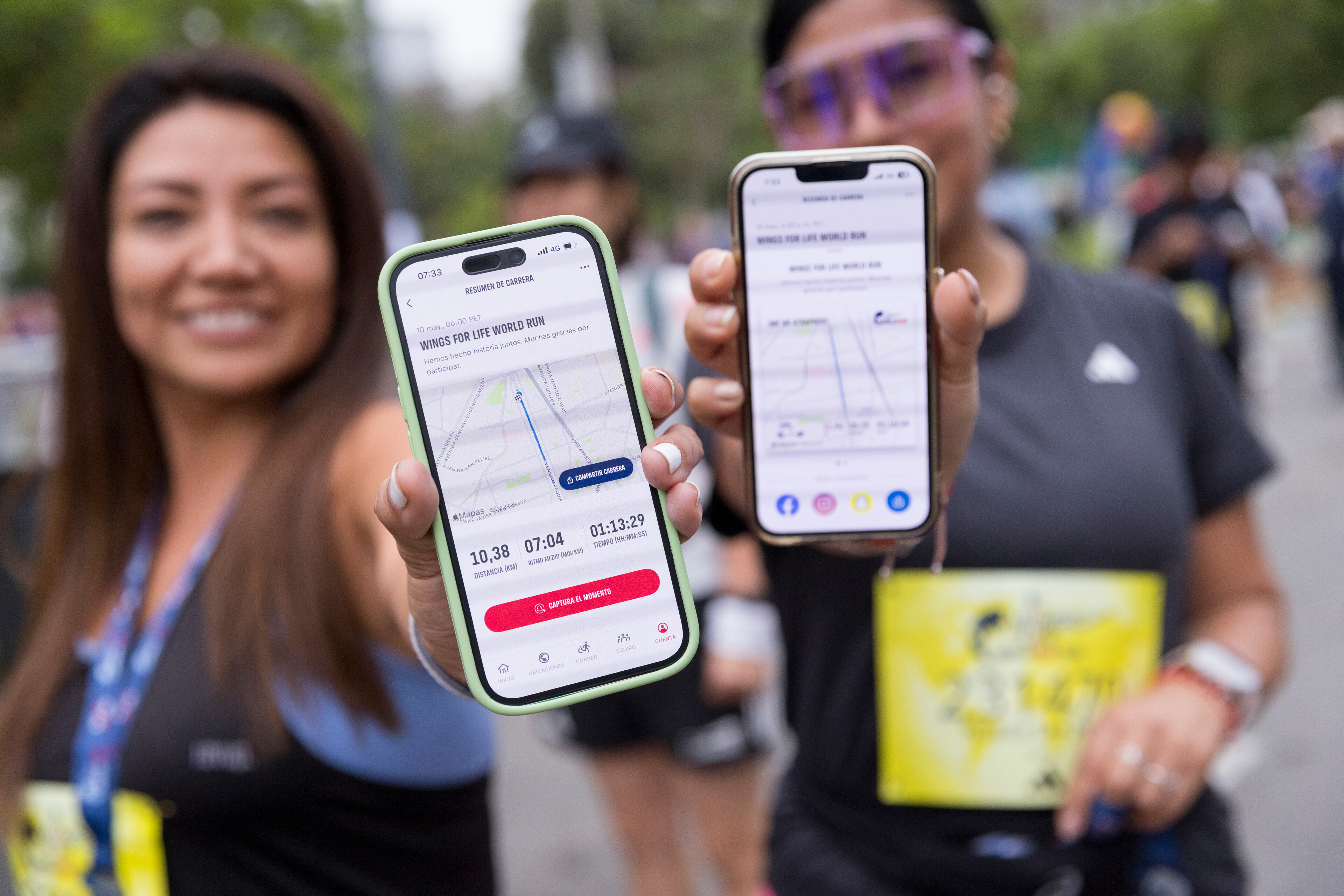 Duas mulheres sorridentes seguram celulares mostrando o aplicativo 