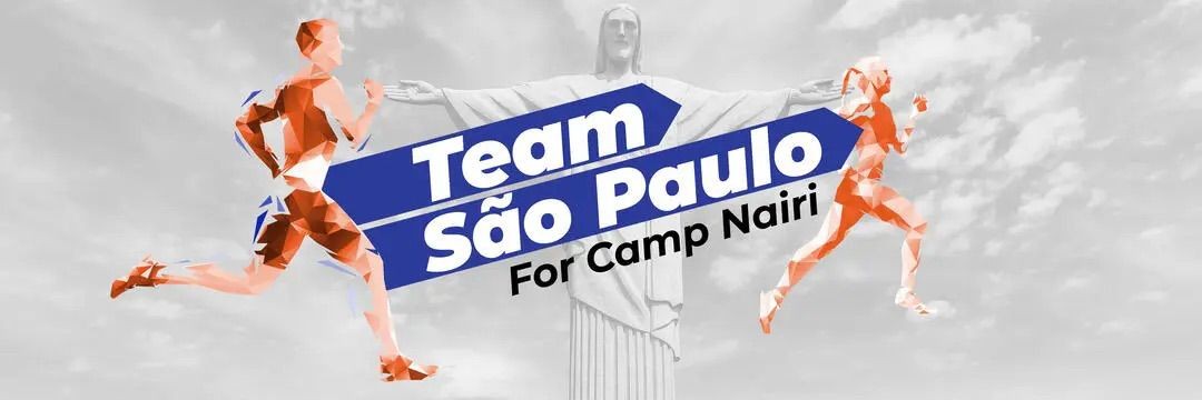 Dois corredores estilizados em tons de laranja e azul, um à esquerda e outro à direita, correm em frente ao Cristo Redentor em cinza. Uma faixa azul com as palavras Team São Paulo For Camp Nairi está centralizada